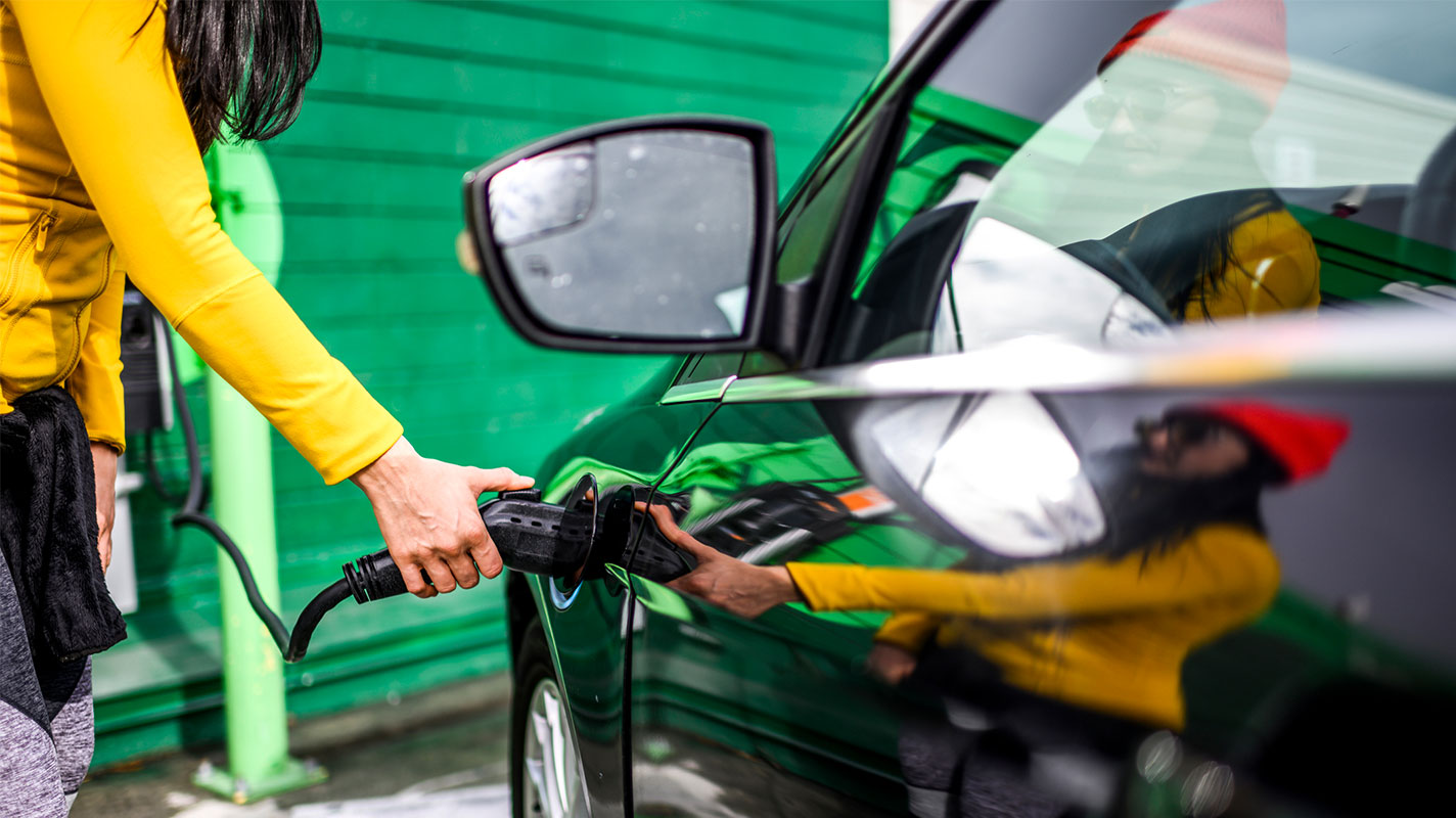 Woman in activewear charging an electric vehicle