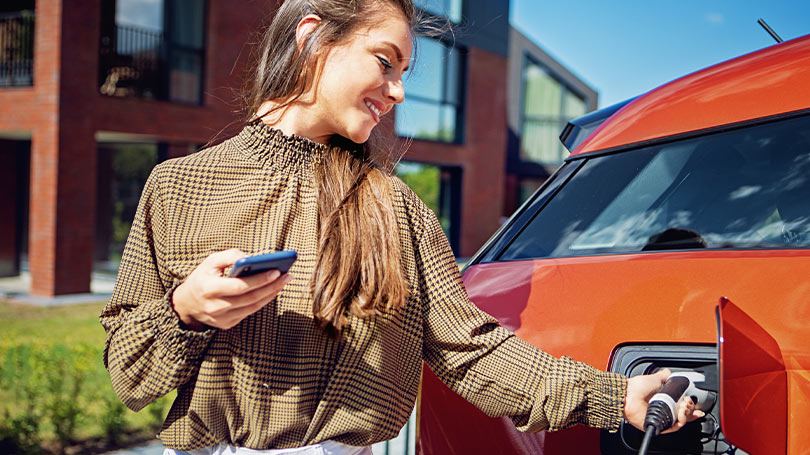 Woman charging EV near multifamily housing