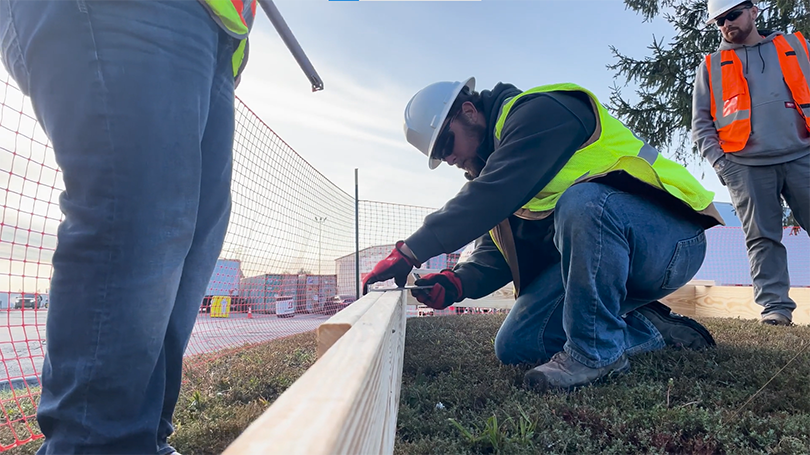 Electric vehicle charging station construction crew measuring frame for concrete pour.