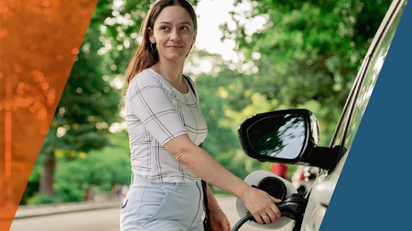 Woman charging car on side of rural road.