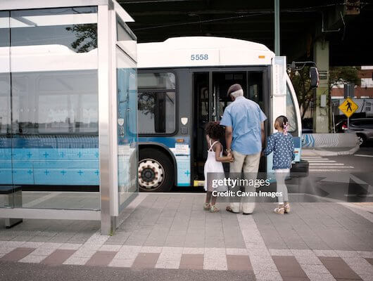 man walking two girls into bus