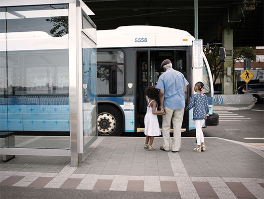 man walking two girls into bus