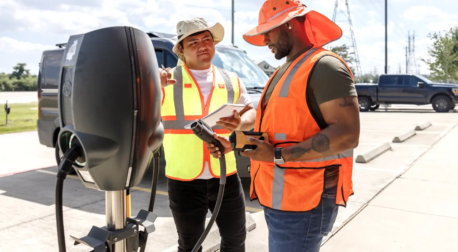 Two utility workers looking at an electric vehicle charger